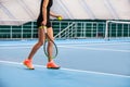 Legs of young girl in a closed tennis court with ball and racket Royalty Free Stock Photo