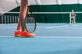 Legs of young girl in a closed tennis court with ball and racket Royalty Free Stock Photo