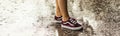 Legs of a young girl in purple sneakers in summer rain