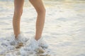 Legs of a young girl on sea and sandy beach Royalty Free Stock Photo