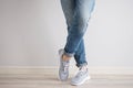 Legs of a young man in jeans and sneakers on a gray background Royalty Free Stock Photo