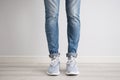 Legs of a young man in jeans and sneakers on a gray background Royalty Free Stock Photo