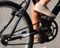 View of the central parts of a bicycle, which is enjoyed by a young man with brown shoes, blue stockings. Royalty Free Stock Photo
