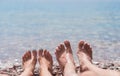 Legs of young man and woman on the beach by the sea. Enjoying the sun on a summer sunny day at the sea. Family vacation concept Royalty Free Stock Photo