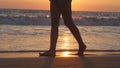 Legs of young woman going along ocean beach during sunrise. Female feet walking barefoot on sea shore at sunset. Girl Royalty Free Stock Photo