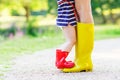 Legs of young woman and her little girl daugher in rainboots