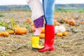 Legs of young woman and her little girl daugher in rainboots.