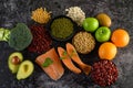 Legumes, broccoli, fruit, and salmon placed on a black cement floor