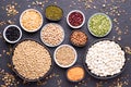 Legumes, lentils, chickpeas and beans assortment in various bowls on black stone background, top view