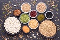 Legumes, lentils, chickpeas and beans assortment in various bowls on black stone background, top view