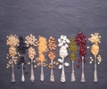 Legumes, lentils, chikpea, dry peas and beans in spoons on stone background. Top view with copy space