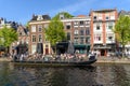 Boat terrace full of people enjoying the sun, food and drinks in the canal of the old town center of Leiden. Blue sky