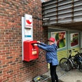 LEIKANGER, NORWAY - 16 JUN 2019: Senior woman puts letter in a postbox Royalty Free Stock Photo