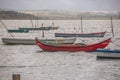 View of traditional fishing boats floating on the edge of the Nazare lagoon, strong wind and rain, in Portugal