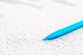 Leisure activity. Close-up of a blue pen on a newspaper crossword puzzle with letters. Royalty Free Stock Photo