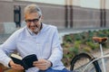 Leisure afternoon in city. man sitting bench and reading book in city Royalty Free Stock Photo