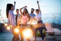 Happy friends with drinks toasting at rooftop party at night