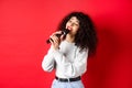 Leisure and hobbies concept. Stylish young woman singing karaoke, looking aside and holding microphone, performing song Royalty Free Stock Photo