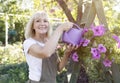 Leisure, lifestyle concept. Happy mature woman watering petunia flowers in pots, gardening in her own summer garden Royalty Free Stock Photo