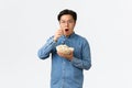 Leisure, lifestyle and people concept. Thrilled and amazed asian guy watching awesome movie or TV series, eating popcorn