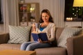 Young woman reading book at home in evening Royalty Free Stock Photo