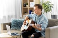 Young man with laptop playing guitar at home Royalty Free Stock Photo