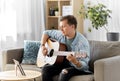 Young man with tablet pc playing guitar at home Royalty Free Stock Photo