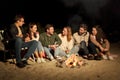 Group of friends sitting at camp fire on beach Royalty Free Stock Photo