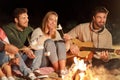 Friends roasting marshmallow and playing guitar Royalty Free Stock Photo