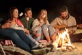 Friends roasting marshmallow and playing guitar Royalty Free Stock Photo