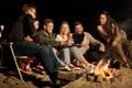 Friends with tablet pc at night camp fire on beach Royalty Free Stock Photo