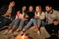 Friends with tablet pc at fire on beach at night Royalty Free Stock Photo