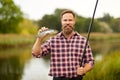 Bearded fisherman with fishing rod and fish catch