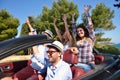 Leisure, road trip, travel and people concept - happy friends driving in cabriolet car along country road Royalty Free Stock Photo