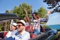 Leisure, road trip, travel and people concept - happy friends driving in cabriolet car along country road Royalty Free Stock Photo