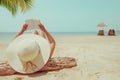 Young woman in straw hat lying sunbathe on a tropical beach, relax with book. Royalty Free Stock Photo