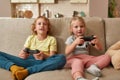 Leisure time. Cheerful kids, little boy and girl playing video games using joystick or controller while sitting together Royalty Free Stock Photo