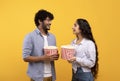 Leisure time together. Happy indian man and woman standing with popcorn, looking and smiling at each other Royalty Free Stock Photo