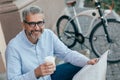 Leisure time in town. man reading newspaper and having cup of coffee, blurred bicycle in background Royalty Free Stock Photo