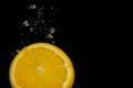 Slice of lemon in water with bubbles and black background