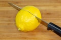 Lemon being sliced in half on a cutting board on a kitchen table Royalty Free Stock Photo