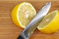 Lemon being sliced in half on a cutting board on a kitchen table Royalty Free Stock Photo