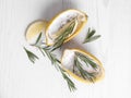 Lemon candles and fresh rosemary on white wooden table, flat lay. Natural homemade repellent