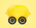 Lemon car concept, lemon with wheels isolated on light yellow background Royalty Free Stock Photo