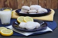 Lemon cookies with powdered sugar with lemons and a glass of mil