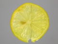 Close-up of slice of yellow lemon fruit on grey background