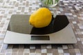 Lemon on digital kitchen scale on table with oilcloth Royalty Free Stock Photo