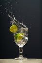 Lemon falling into a glass of transparent water causing splashes upwards. Isolated on gray background Royalty Free Stock Photo