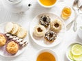 Lemon green tea and sweets - banana muffins, cookies with caramel and nuts, donuts with chocolate and lemon glaze, tea set on whit Royalty Free Stock Photo