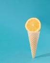 Lemon in ice cream cone. Summer coming design idea. Aesthetic refreshment on a sky blue background. Fruity ice cream